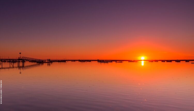 sunset over a calm sea by Algarve's barrier islands