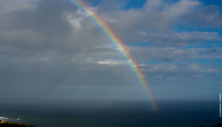 Rainbow over ocean with clouds in the sky