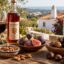 Autumn in the Algarve harvest table with red wine, medronho, fresh figs, almonds and roasted chestnuts overlooking whitewashed villas and the sea
